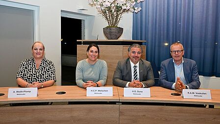 Foto van de vier wethouders achter hun tafel in de raadzaal