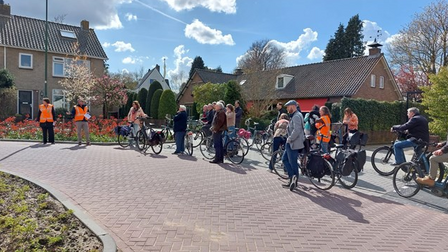 Foto van een groep mensen stilstaand op de fiets met drie personen met een oranje hesje.